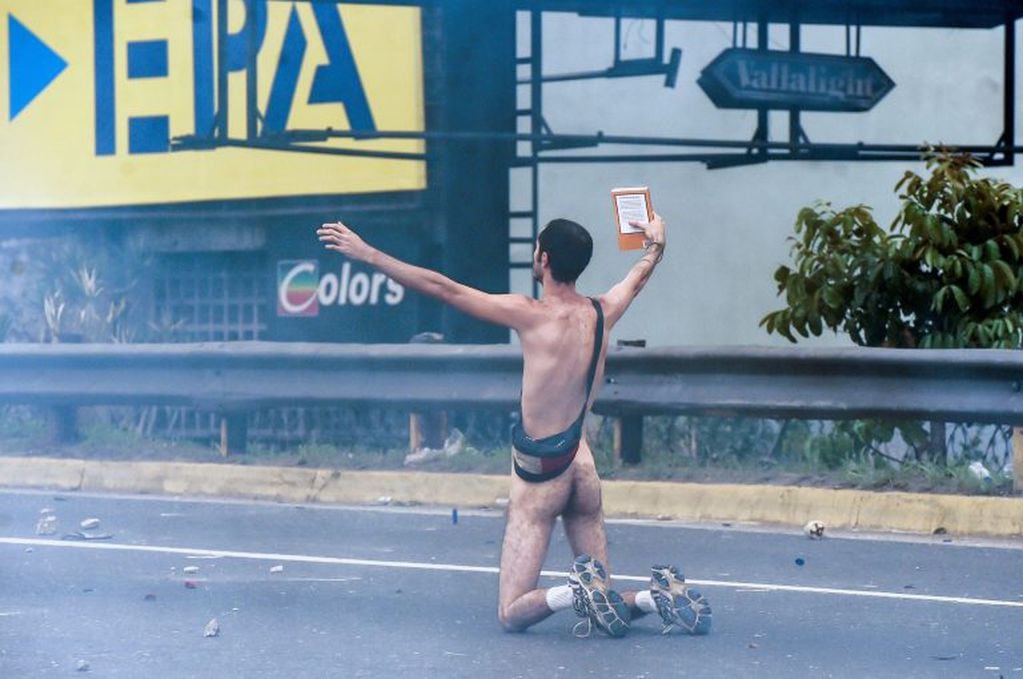 TOPSHOT - EDITORS NOTE: Graphic content / A naked demonstrator takes part in a protest against Venezuelan President Nicolas Maduro, in Caracas on April 20, 2017.
Venezuelan riot police fired tear gas Thursday at groups of protesters seeking to oust Presid