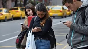 Jóvenes leen noticias en el teléfono celular