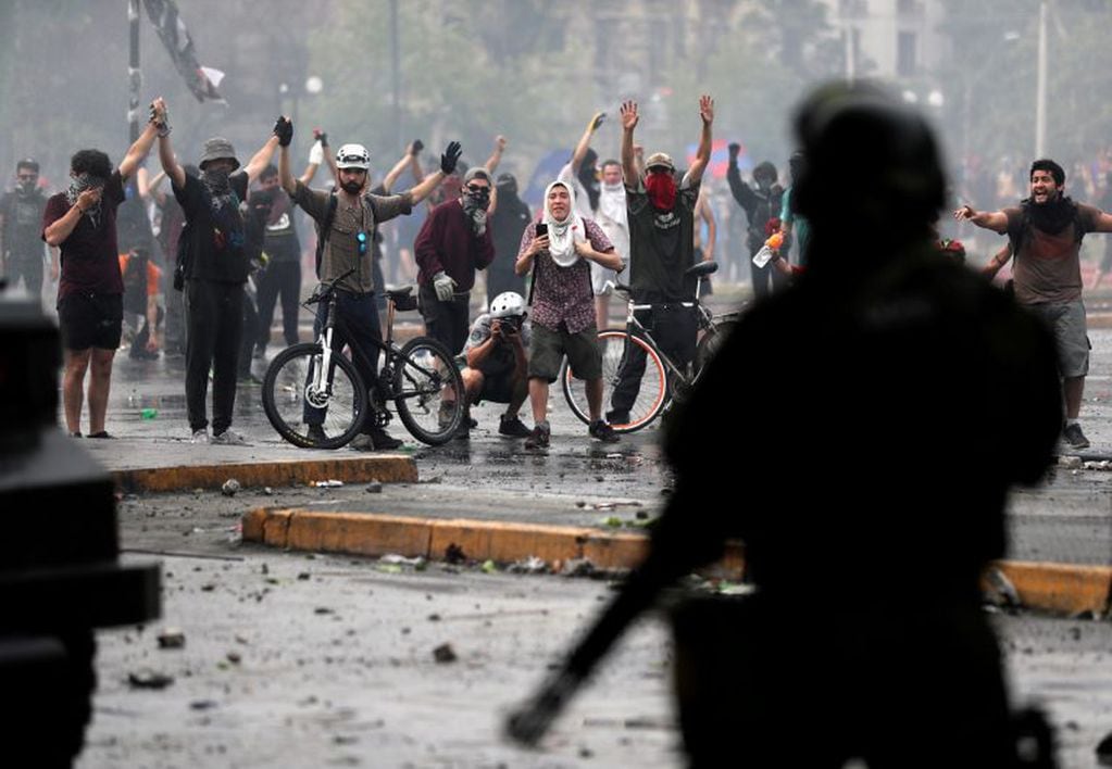 La gente levanta los brazos frente a la policía antidisturbios, durante una protesta enn Santiago de Chile, el 23 de octubre de 2019. Crédito: REUTERS / Ivan Alvarado.