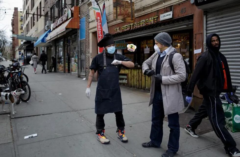 Chef Jorge Cardenas shares an elbow bump with regular Ix customer Lorenzo Bernasconi outside of Ix restaurant in the Brooklyn borough of New York City, U.S., April 2, 2020 amid the coronavirus disease (COVID-19) outbreak. Picture taken April 2, 2020.  REUTERS/Anna Watts  NO RESALES. NO ARCHIVES