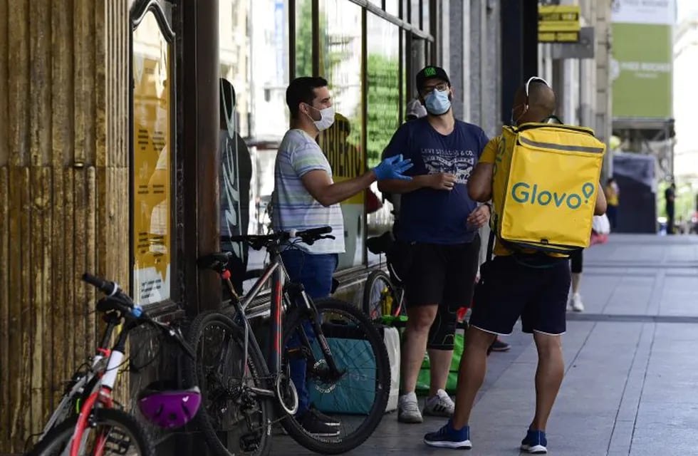 Employees of delivery services wearing masks chat as they wait outside a fast food restaurant in Madrid on May 21, 2020 as wearing masks became obligatory in public where social distancing is not possible. - Everyone aged six and above must wear a mask in public where social distancing is not possible, officials said in Spain, where the epidemic has claimed nearly 28,000 lives although the death rate has slowed and the lockdown is being gradually eased. (Photo by JAVIER SORIANO / AFP)