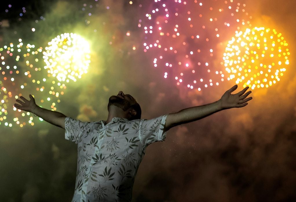 Un hombre celebra el inicio del año nuevo, con el telón de fondo de la explosión de fuegos artificiales en el fondo sobre la playa de Copacabana en Río de Janeiro, Brasil