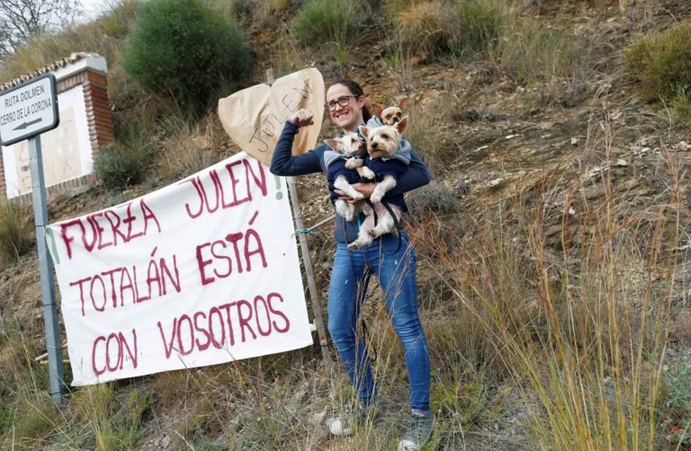 Maria Guarrochena, 36, gestures with her dogs next to a banner that reads \
