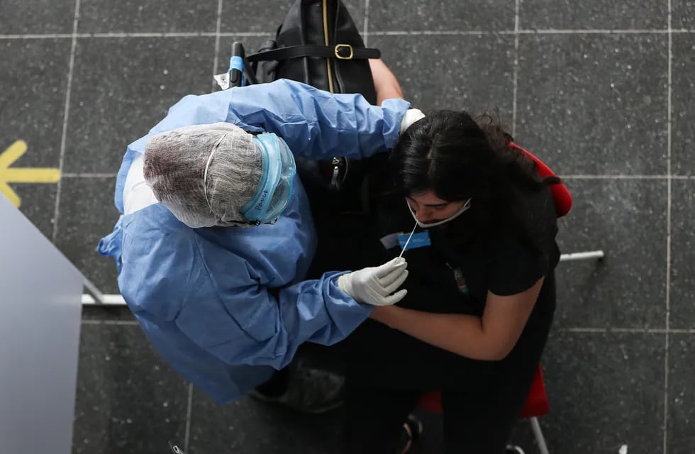 Una persona del personal sanitario realiza una prueba de coronavirus a una viajera en una terminal de transporte en Buenos Aires. (Foto: EFE/ Juan Ignacio Roncoroni)