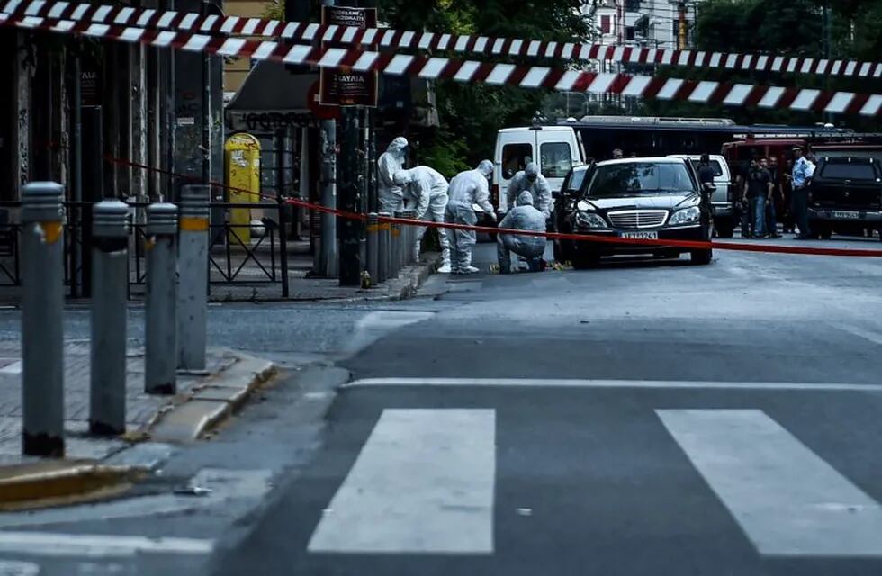 Forensic experts of the police search for evidence in and around the car of Greek former prime minister Lucas Papademos in Athens on May 25, 2017, after Papademos was hurt when an explosive device went off inside his car. nState news agency ANA said Papademos was undergoing surgery for abdominal and leg injuries at an Athens hospital. State TV ERT earlier reported that he also had trouble breathing, but his life was not in danger. n / AFP PHOTO / Eleftherios Elis