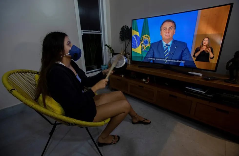AME7670. BRASILIA (BRASIL), 24/03/2020.- Una mujer con una máscara protesta golpeando una olla durante una declaración televisda del presidente de Brasil, Jair Bolsonaro, este martes en Brasilia (Brasil). Bolsonaro pidió este martes que el país deje atrás el \