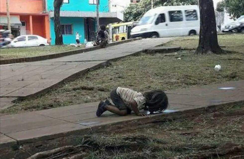 Imagen archivo. Nena guaraní tomando agua de un charco del piso.