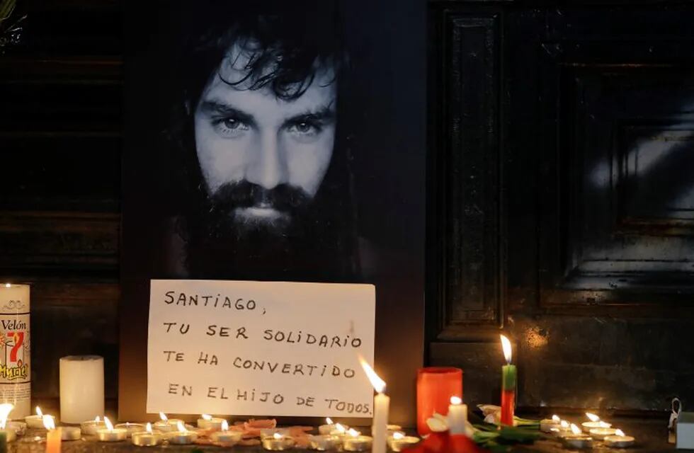 A photo of missing activist Santiago Maldonado is surrounded by candles and a message that reads in Spanish: \