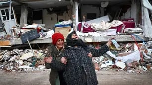 Mujeres reaccionan en el lugar de un edificio derrumbado tras un gran terremoto en el distrito de Elbistan de Kahramanmaras, Turquía