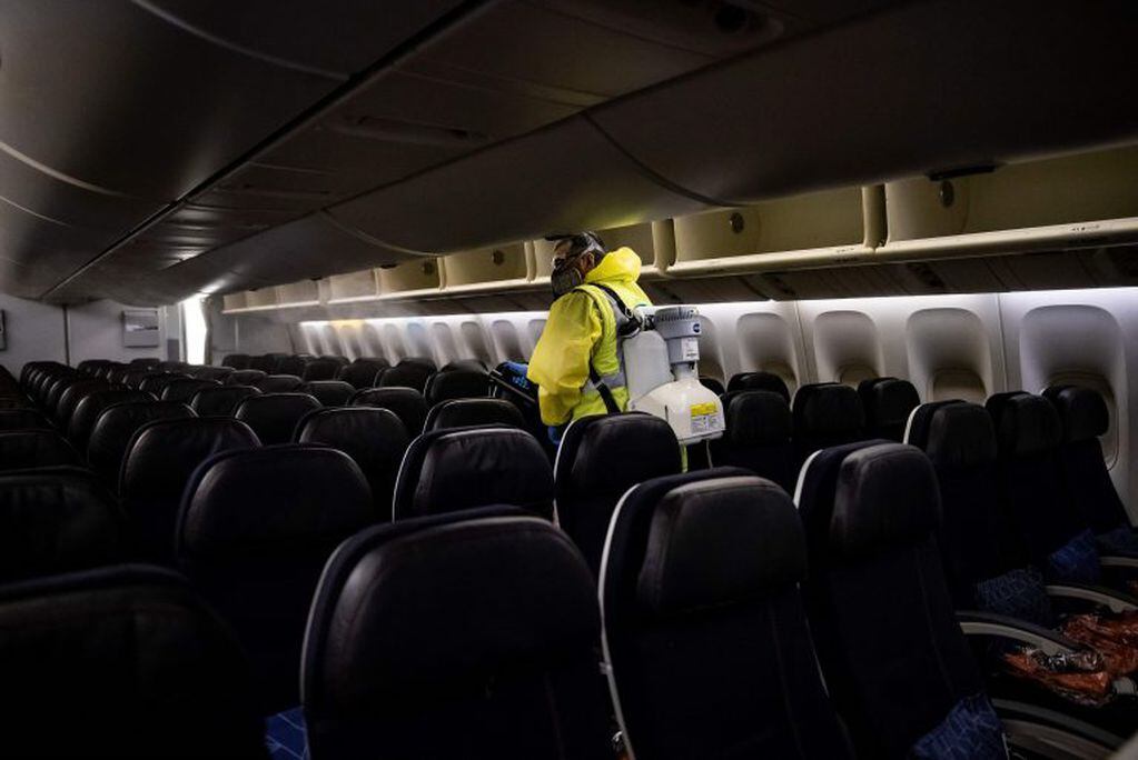Un trabajador desinfecta un avión de Air France en el aeropuerto Charles de Gaulle, en París (Ian LANGSDON / POOL / AFP)