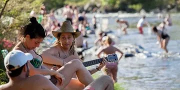 Sol y río. Con la guitarra, junto al agua, turistas disfrutan ayer en el balneario Mate de Luna, de Santa Rosa de Calamuchita (LaVoz).