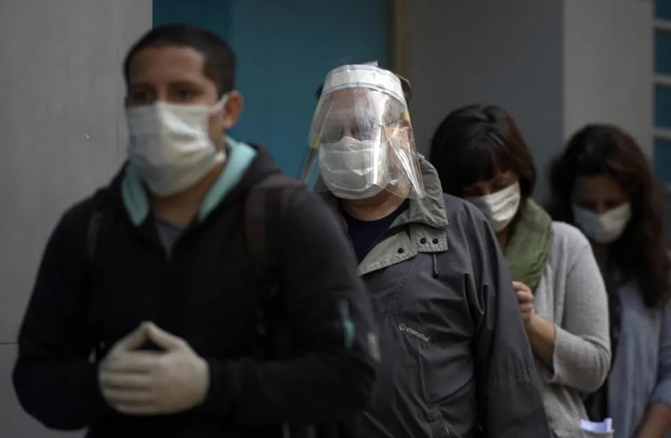 People wear face masks as thet queue to use an ATM in Buenos Aires, on April 17, 2020 amid the COVID-19 coronavirus pandemic. (Photo by JUAN MABROMATA / AFP)