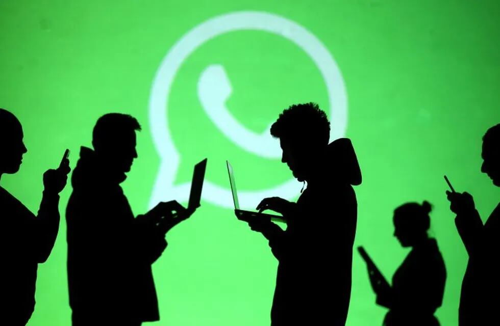 REFILE - CLARIFYING CAPTION Silhouettes of laptop and mobile device users are seen next to a screen projection of Whatsapp logo in this picture illustration taken March 28, 2018.  REUTERS/Dado Ruvic/Illustration   internet redes sociales logos empresas ilustracion gente usando redes sociales a traves de celulares y notebooks