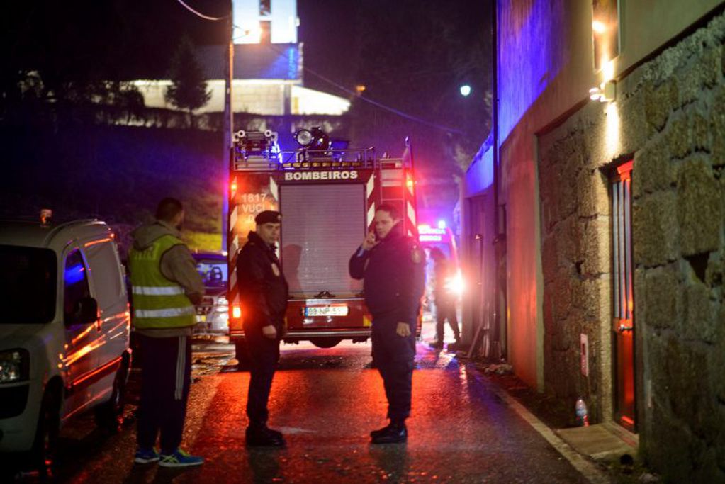 Policemen stand outside the building, at right, where a heater exploded killing people in the village of Vila Nova da Rainha, outside Tondela, northern Portugal, in the early hours of Sunday, Jan. 14 2018. A wood-burning stove exploded and started a fire late Saturday at the packed premises of a local residents' association in the north of Portugal, officials said.(AP Photo/Sergio Azenha)