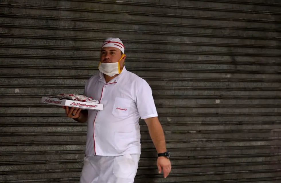 A delivery man with a pizza walks past a closed store in Buenos Aires, Argentina, Wednesday, April 1, 2020, during a government ordered lock down to contain the spread of the new coronavirus. COVID-19 disease causes mild or moderate symptoms for most people, but for some, especially older adults and people with existing health problems, it can cause more severe illness or death. (AP Photo/Natacha Pisarenko)
