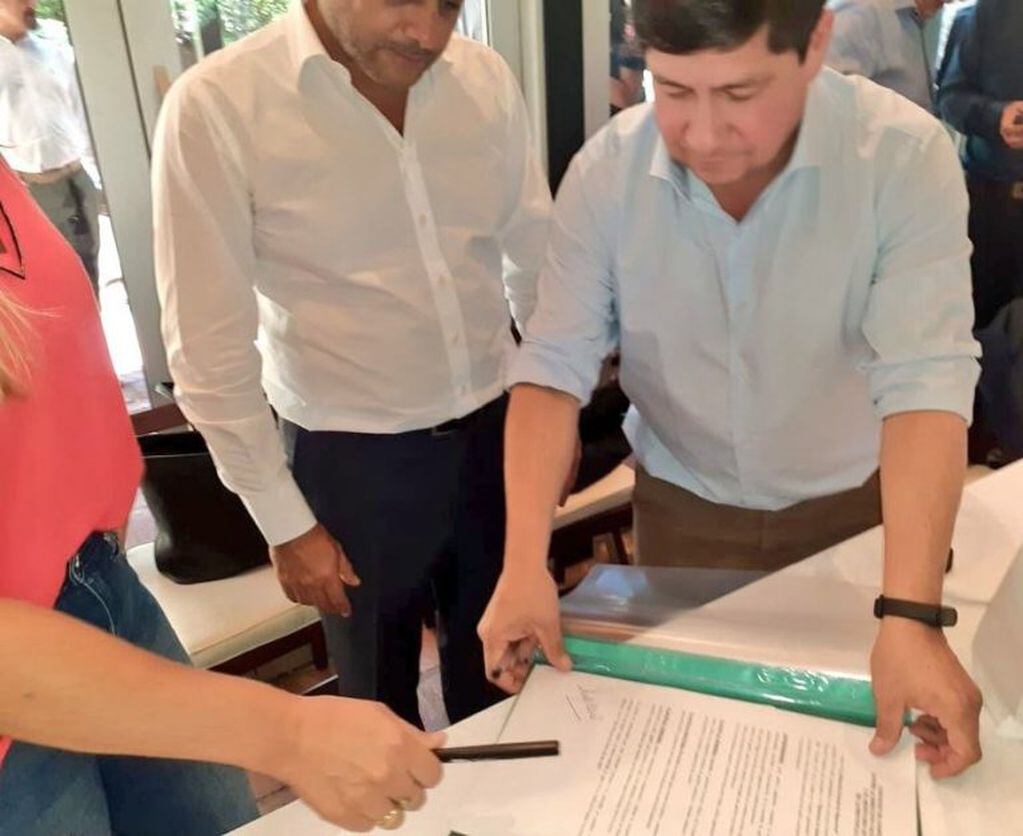 El ministro de Salud Oscar Alarcón firma el convenio con la titular de Migraciones, doctora Carignano. (Twitter)