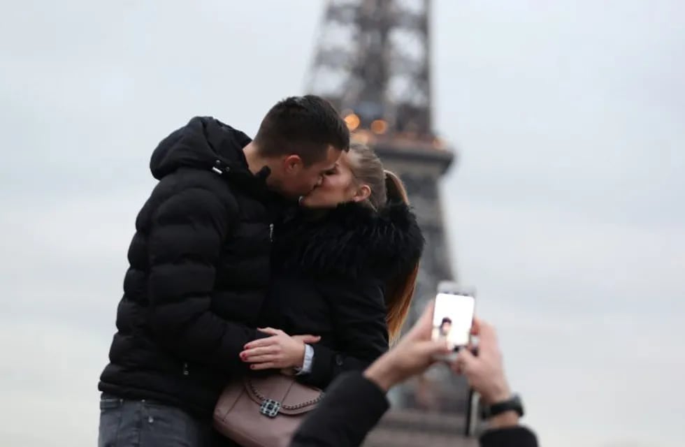 A couple of tourists kiss as they pose with the Eiffel Tower in background at the Trocadero esplanade, in Paris on December 31, 2019. (Photo by Zakaria ABDELKAFI / AFP) paris francia  turismo en la torre eiffel pareja beso besandose turistas esplanada trocadero