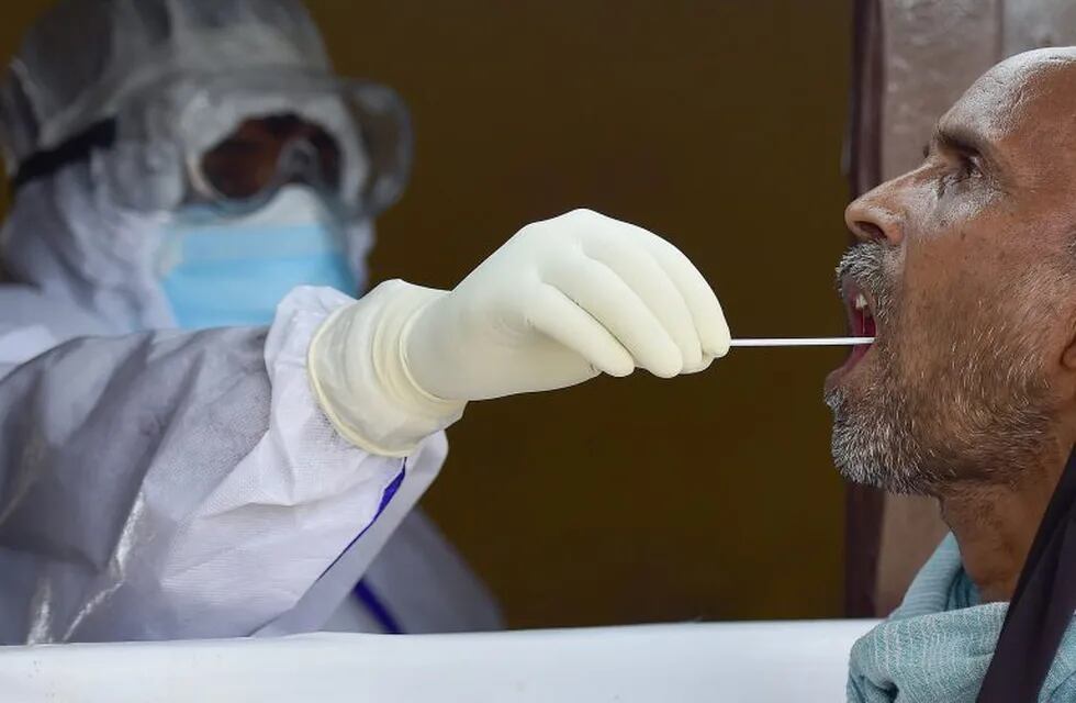 A health official takes a swab sample from a man to test for the COVID-19 coronavirus at a testing point in Allahabad on August 7, 2020. - India's official coronavirus case tally hit two million on August 7, doubling in three weeks as the pandemic sweeps into smaller cities and rural areas, with experts warning the real toll could be much higher. (Photo by SANJAY KANOJIA / AFP)