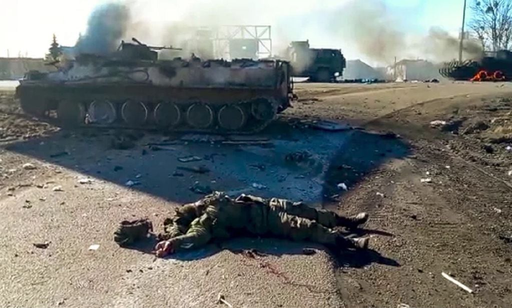 En esta foto tomada de un video publicado por el Servicio de Prensa del Departamento de Policía de Ucrania, el cuerpo de un soldado muerto yace en el suelo junto a vehículos militares destrozados