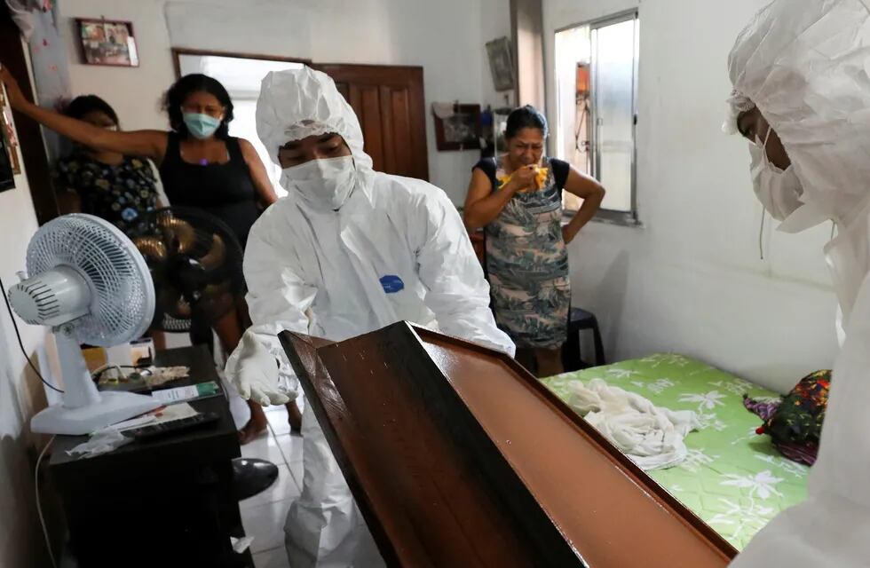 Personal con la indumentaria correspondiente prepara el cajón de una víctima de coronavirus en Manaos Foto: REUTERS/Bruno Kelly