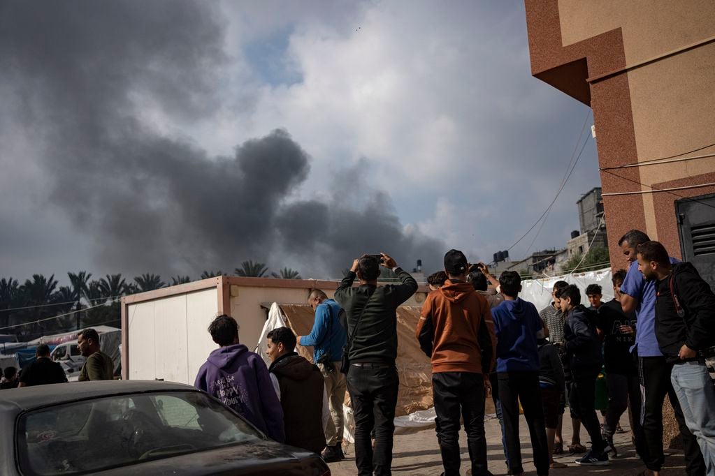 Palestinos observan el humo tras un ataque aéreo israelí en Jan Yunis, en la Franja de Gaza, el viernes 1 de diciembre de 2023. (AP Foto/Fatima Shbair)