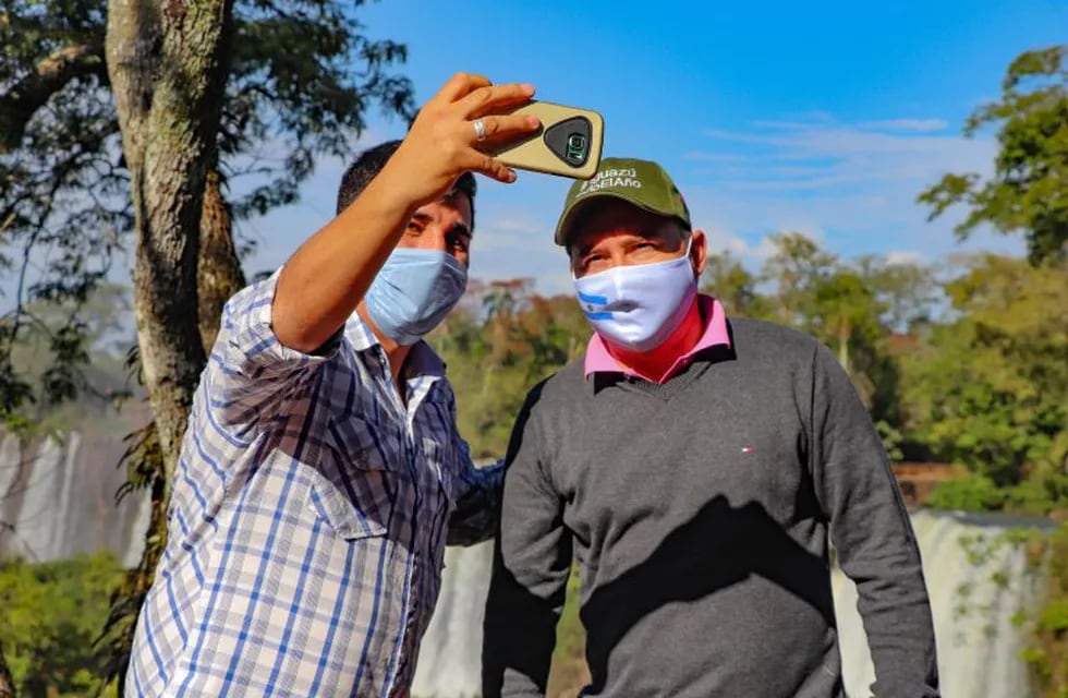 AME2380. PARQUE NACIONAL IGUAZÚ (ARGENTINA), 13/07/2020.- Fotografía cedida este lunes por Iturem Iguazú que muestra a dos turistas mientras se toman una selfi en el Parque Nacional Iguazú (Argentina). La parte argentina de las Cataratas del Iguazú volvió a recibir visitantes tras cuatro meses de confinamiento en el que el Parque Nacional estuvo cerrado al público. Por primera vez en más de cien días, el rumor del agua estuvo acompañado por el de las voces de las familias que, protegidos por mascarillas, recorrieron las pasarelas o sendas situadas en medio de la selva y disfrutaron de las vistas de la que es considerada una de las Maravillas Naturales del Mundo. EFE/ Iturem Iguazú /SOLO USO EDITORIAL /NO VENTAS