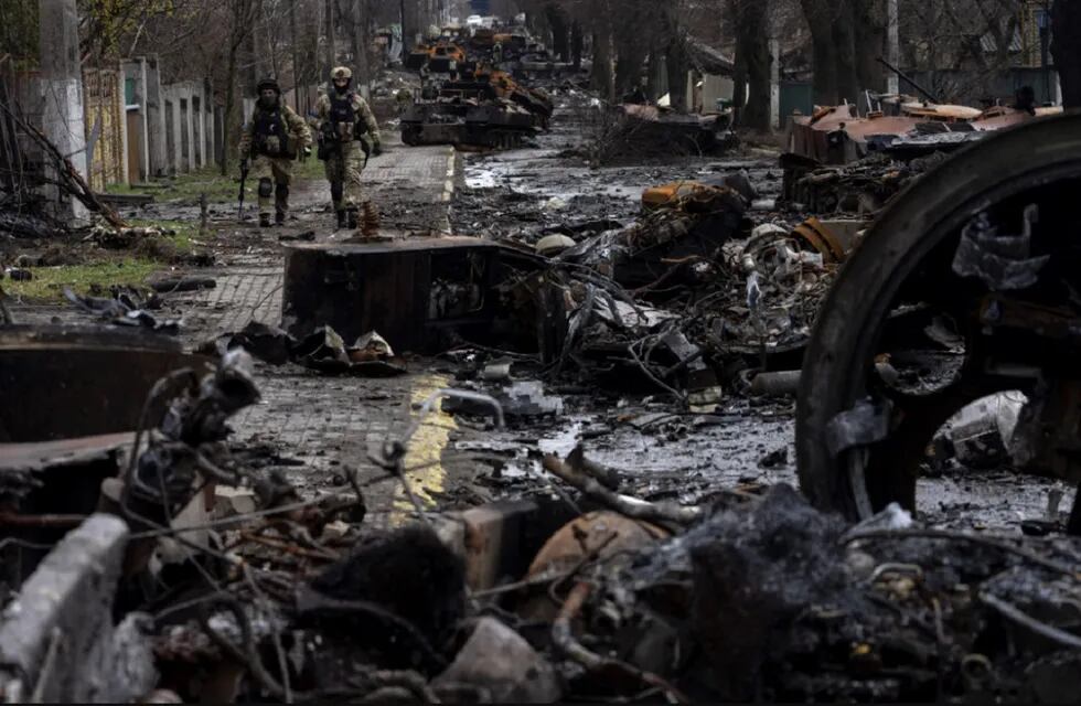 Soldados caminan entre tanques rusos destruidos en Bucha, en las afueras de Kiev. Allí denuncian que se cometieron crímenes de guerra.  (AP)