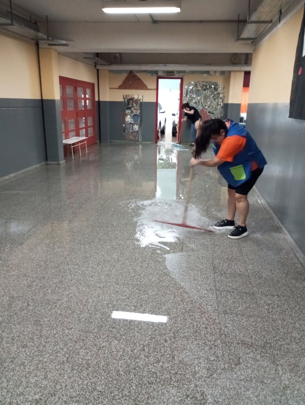 Docentes de Córdoba trapeando la escuela inundada. 