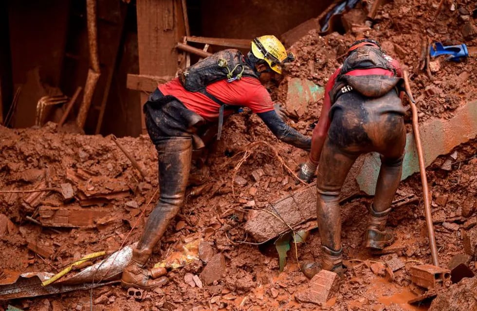 Firefighters search for missing persons after a landslide in Vila Bernadete, Belo Horizonte, Minas Gerais state, Brazil, on January 26, 2020. - A landslide buried several houses in Vila Bernadete Friday, leaving 4 dead and 7 missing. Two days of torrential rains in Minas Gerais state have left at least 30 people killed, several injured, 17 missing and more than 2,500 homeless following a series of landslides and house collapses, Civil Defence officials said. (Photo by DOUGLAS MAGNO / AFP)