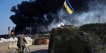 Ucrania. Un hombre anda en bicicleta mientras, de fondo, se levanta una columna de humo negra tras ataques rusos en las afueras de Kiev. (AP / Rodrigo Abd)