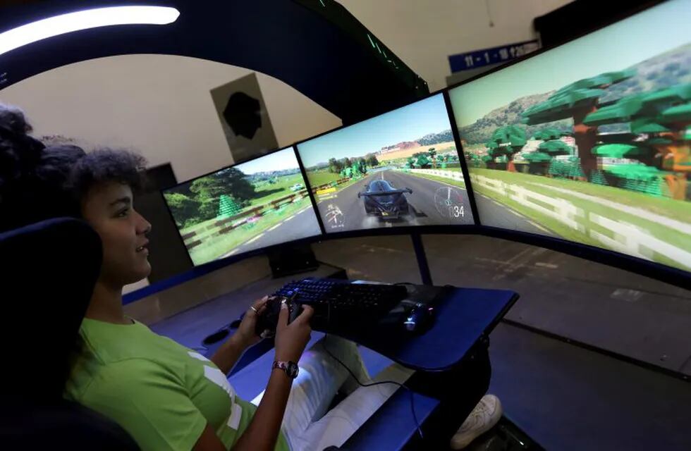 A staff member plays a racing game in a 'Predator Thronos' gaming seat at the at the IFA 2019 tech fair in Berlin, Germany, Wednesday, Sept. 4, 2019. The IFA takes place in Berlin from Sept. 6 until Sept. 11, 2019. (AP Photo/Michael Sohn)