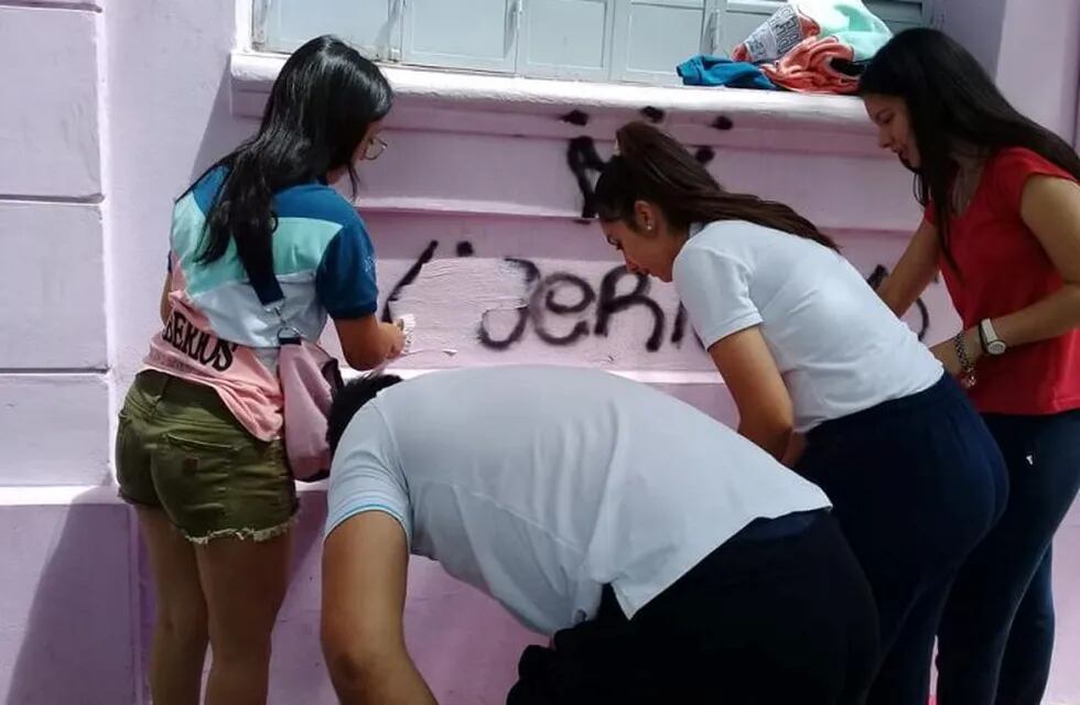Liberios y sus padres arreglando las pintadas en la escuela Paula Dominguez de Bazán.