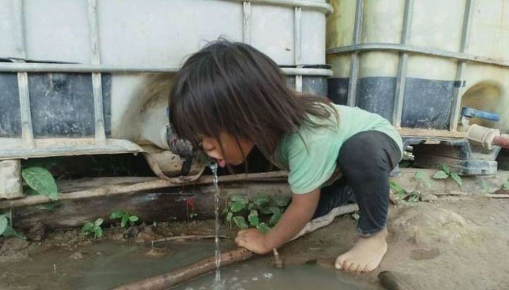Un niño de la comunidad wichí bebe agua de un tanque de asistencia.