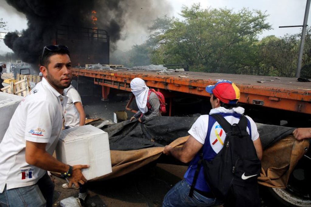 Las personas intentan salvar la ayuda humanitaria antes que se incendie en el puente de Cucuta, en la frontera con Venezuela (REUTERS/Marco Bello)