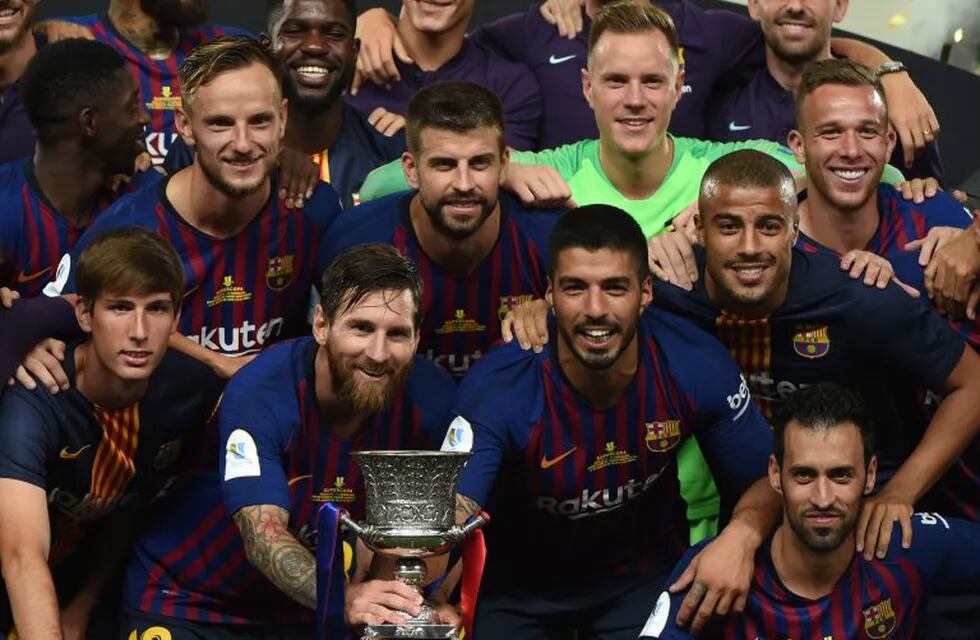 Barcelona's Argentinian forward Lionel Messi (C) carries the cup as they celebrate at the end of the Spanish Super Cup final between Sevilla FC and FC Barcelona at Ibn Batouta Stadium in the Moroccan city of Tangiers on August 12, 2018. - Barcelona defeated Sevilla 2-1 to win the Spanish Super Cup. (Photo by FADEL SENNA / AFP)