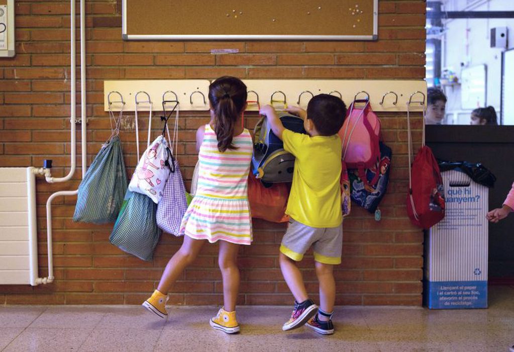 Dos niños cuelgan sus mochilas al volver a la escuela (Foto: EFE/Enric Fontcuberta)