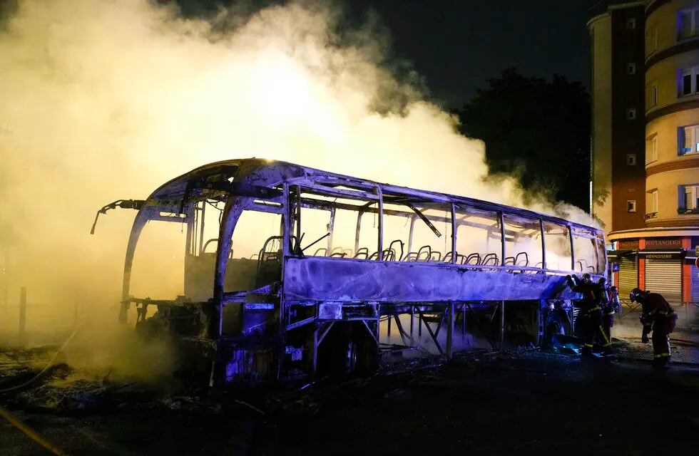 Bomberos arrojan agua a un autobús quemado, el sábado 1 de julio de 2023, en Nanterre, en las afueras de París, Francia. (AP Foto/Lewis Joly)