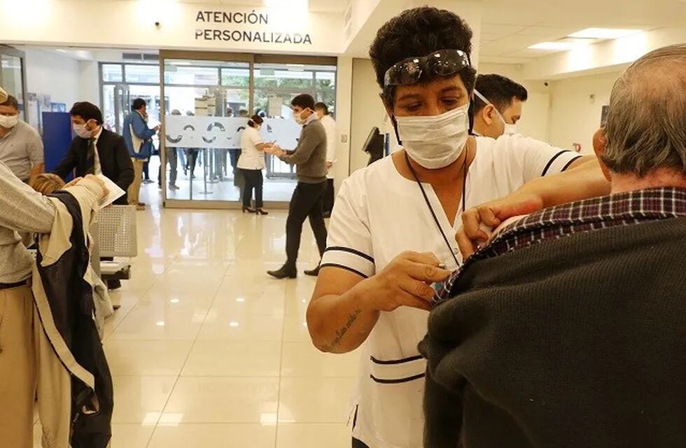 Jubilados reciben la vacuna contra la gripe y el neumococo, mientras se encuentran en los bancos cobrando sus haberes.