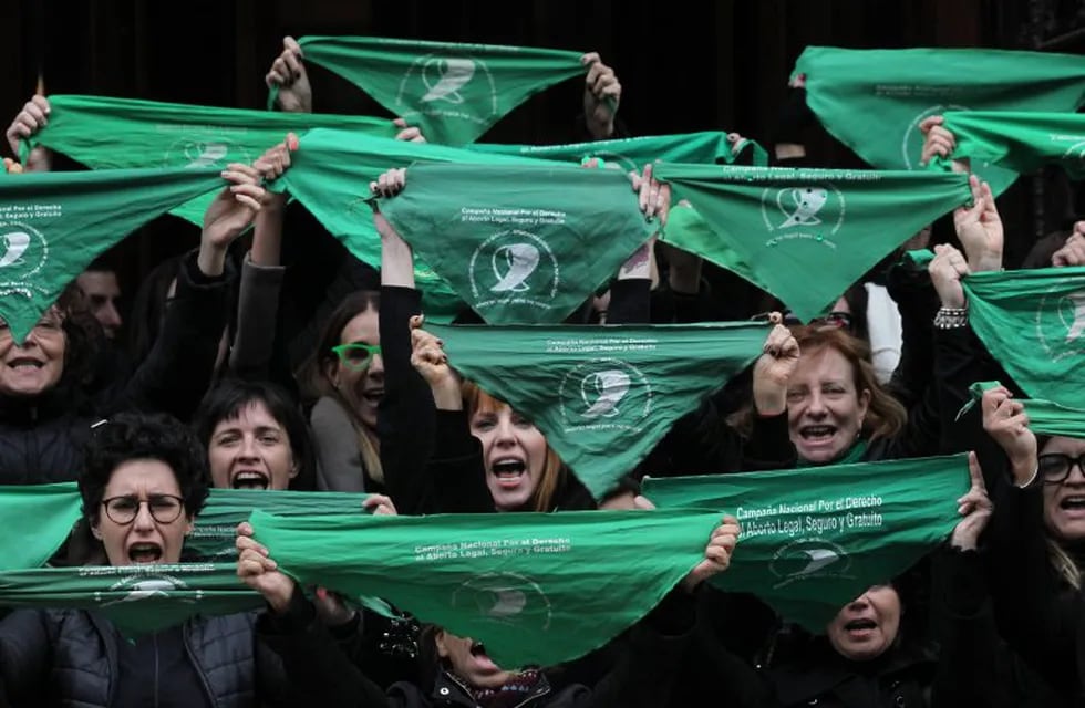 Activistas por la despenalización del aborto sostienen pañuelos verdes durante una marcha para conmemorar su lucha.