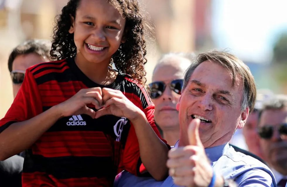 TOPSHOT - Brazilian President Jair Bolsonaro (R) poses with Yasmin Alves -who appeared in a video allegedly refusing to greet him, but already denied-, during a visit to her family house in the outskirts of Brasília, Brazil, on April 27, 2019. - Bolsonrao had received Yasmin at the Planalto Palace earlier this week and presented her the Flamengo jersey she is wearing. (Photo by Sergio LIMA / AFP)