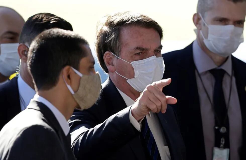 Brazil's President Jair Bolsonaro wears a face mask as he speaks to the press upon departure from the official residence of Alvorada palace in Brasilia, Brazil, Monday, May 11, 2020. Starting Monday, the capital city's government will fine or jail those who do not wear a face mask in public, amid the spread of the new coronavirus. (AP Photo/Eraldo Peres)