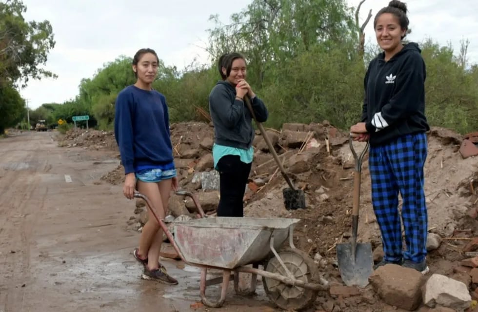 Andrea (23), Daniela (20) y Sara (18) están acarreando tierra que acumularon en el frente de su vivienda luego del terremoto.