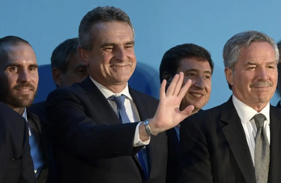 Argentina's new Defense Minister Agustin Rossi (C) waves next to Argentina's new Economy Minister Martin Guzman (L) and Argentina's Foreign Minister Felipe Sola (R), during their swearing in ceremony at the Casa Rosada presidential palace, in Buenos Aires, on December 10, 2019. - Center-leftist Alberto Fernandez vowed to put his people first ahead of debt repayments after he was sworn in as Argentina's president on Tuesday to singing and applause from lawmakers and supporters. (Photo by JUAN MABROMATA / AFP)