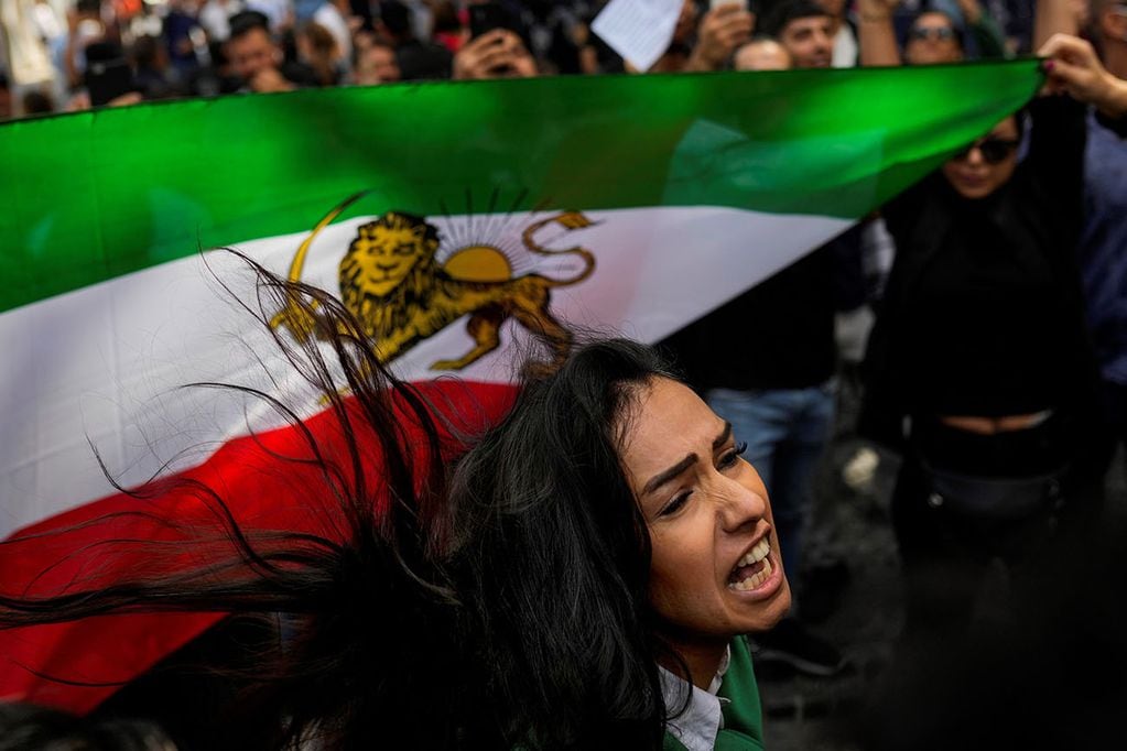 Una mujer grita consignas junto a una bandera iraní afuera del consulado general de Irán en Estambul, Turquía.