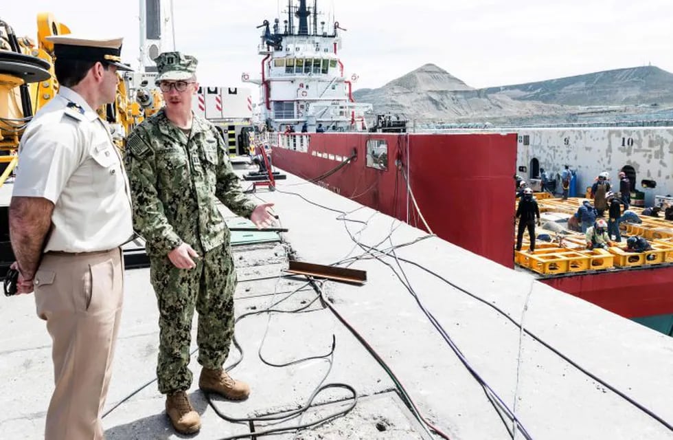 US Navy Karl Schonberd (R) talks with a member of Prefectura Naval Argentina while workers weld the deck of the Sophie Siem vessel where members of the U.S. Navy Undersea Rescue Command (URC) will install the Submarine Rescue Diving and Recompression System (SRDRS) with a deep diving rescue vehicle, the Pressurized Rescue Module (PRM), to support the Argentine government's search and rescue efforts for the missing Argentine submarine ARA San Juan, in Comodoro Rivadavia, Chubut, Argentina on November 24, 2017. chubut comodoro rivadavia Karl Schonberd desaparicion del submarino ARA San Juan operativo operacion busqueda rescate ayuda internacional ayuda de la marina de eeuu