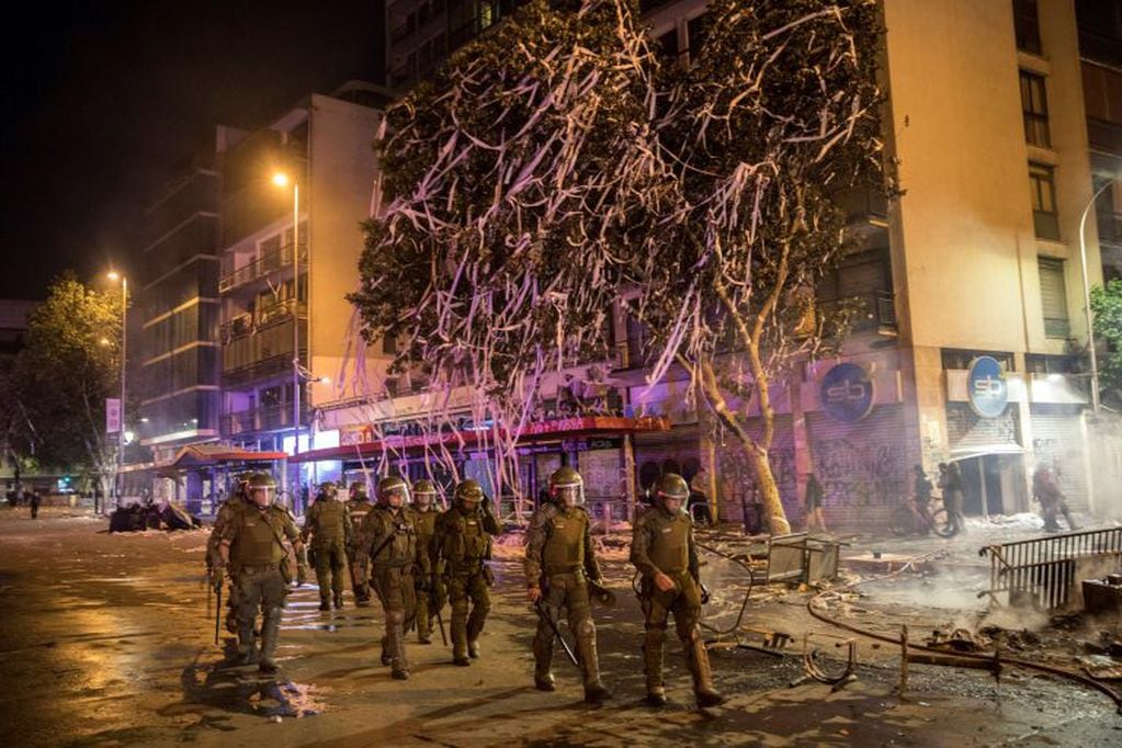 Police walk amid the destruction caused during anti-government protests in Santiago, Chile, Monday, Oct. 28, 2019. Fresh protests and attacks on businesses erupted in Chile Monday despite President Sebastián Piñera's replacement of eight important Cabinet ministers with more centrist figures, and his attempts to assure the country that he had heard calls for greater equality and improved social services. (AP Photo/Rodrigo Abd)