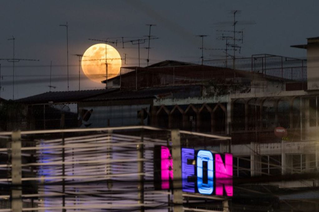 TOPSHOT - A full moon rises over the horizon above residential and commercial buildings in Bangkok on January 31, 2018. 
Skywatchers were hoping for a rare lunar eclipse that combines three unusual events -- a blue moon, a super moon and a total eclipse -- which was to make for a large crimson moon viewable in many corners of the globe. / AFP PHOTO / Roberto SCHMIDT