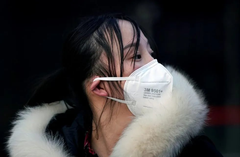 Una mujer porta una máscara al llegar a una estación de trenes en Shanghai, China,