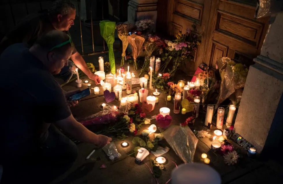 Two men light candles at a makeshift memorial as they take part of a candle lit vigil in honor of those who lost their lives or were wounded in a shooting in Dayton, Ohio on August 4, 2019. - The United States mourned Sunday for victims of two mass shootings that killed 29 people in less than 24 hours as debate raged over whether President Donald Trump's rhetoric was partly to blame for surging gun violence. The rampages turned innocent snippets of everyday life into nightmares of bloodshed: 20 people were shot dead while shopping at a crowded Walmart in El Paso, Texas on Saturday morning, and nine more outside a bar in a popular nightlife district in Dayton, Ohio just 13 hours later. (Photo by Megan JELINGER / AFP)