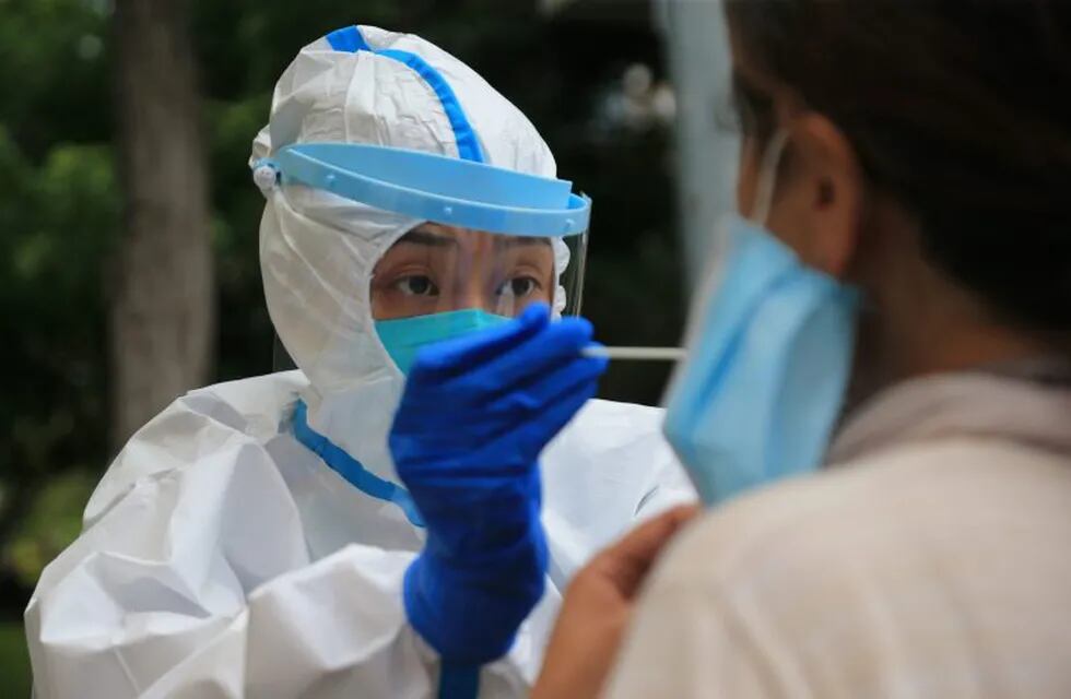 This photo taken on July 26, 2020 shows a health worker carrying out a COVID-19 coronavirus test in Dalian, in China's northeast Liaoning province. - China recorded 61 new coronavirus cases on July 27 -- the highest daily figure since April -- propelled by clusters in three separate regions that have sparked fears of a fresh wave. (Photo by STR / AFP) / China OUT